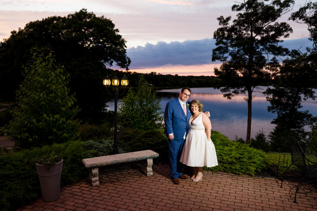 A bride and groom on a patio at sunset overlooking a lake at Rhode Island wedding venue Crystal Lake