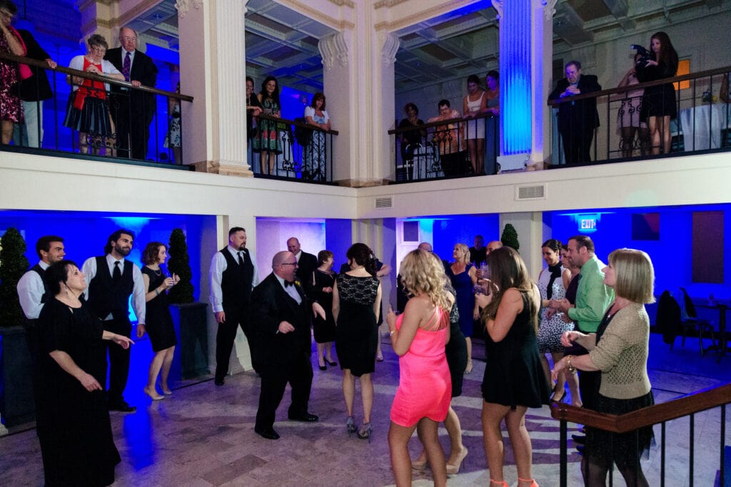 A two story dance floor at a wedding with blue uplighting