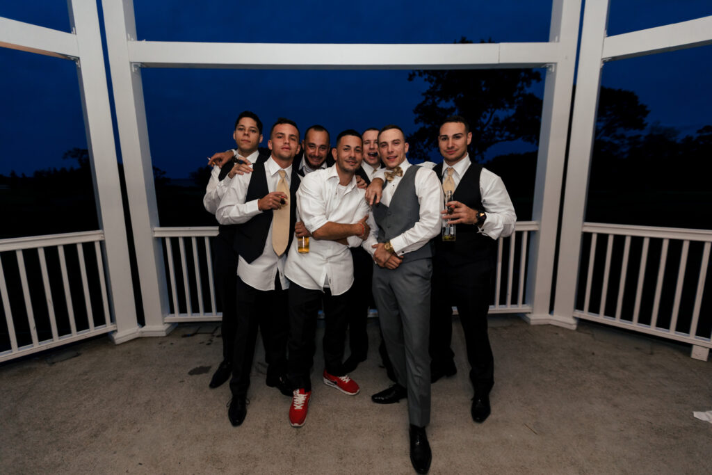 A groom and a bunch of guys on an outdoor patio at dusk