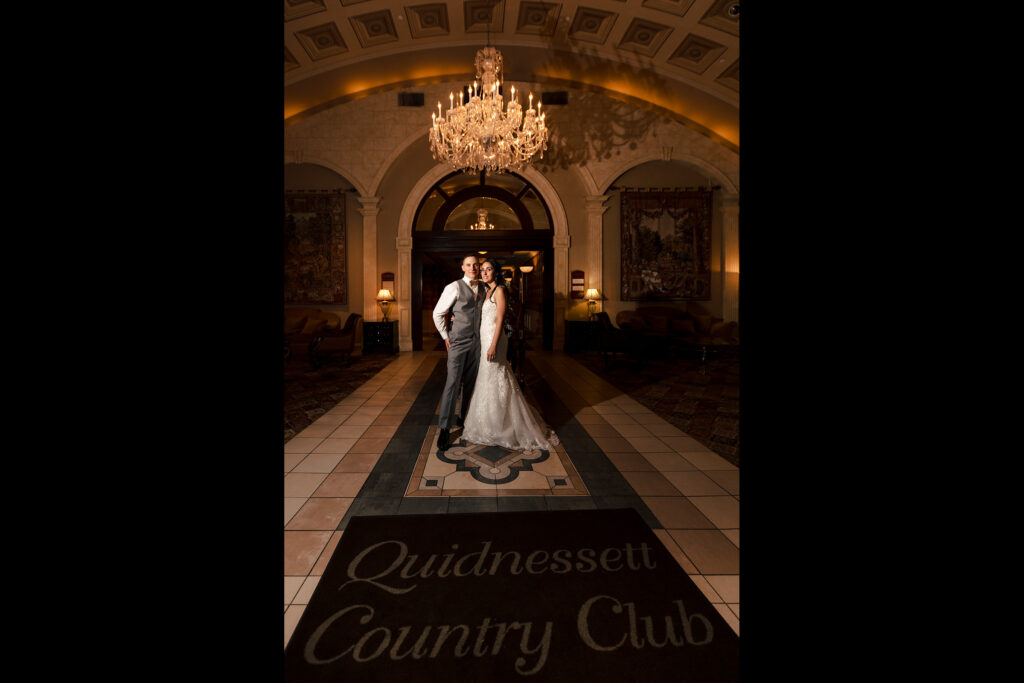 A bride and groom standing in the lobby at quidnessett country club