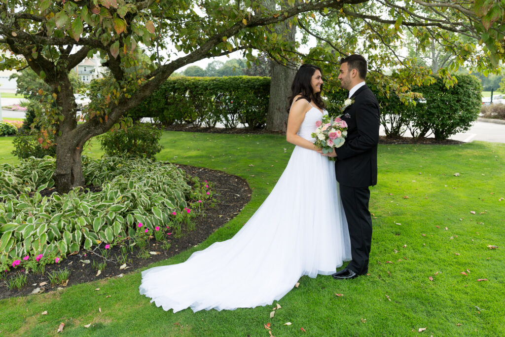 A bride and groom standing under a green tree