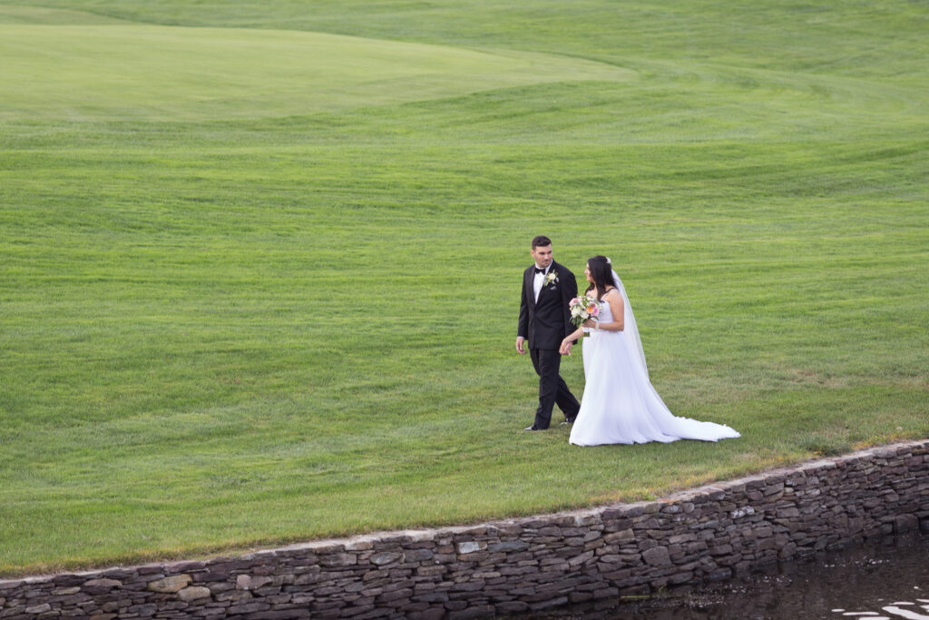 A bride and groom walking on a golf course