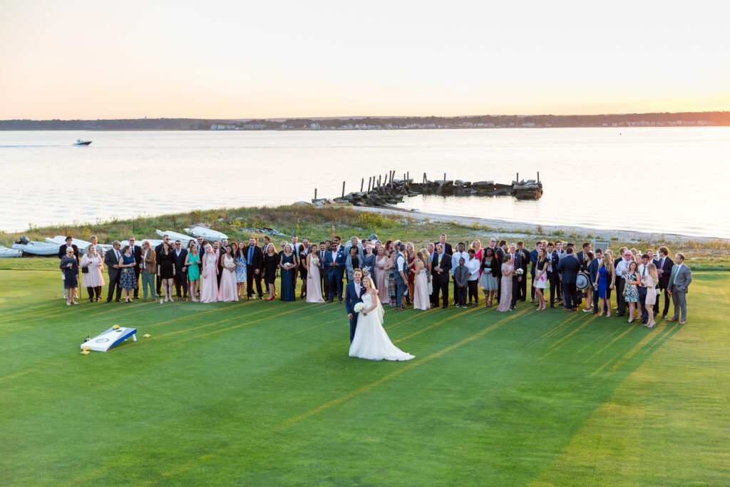 A large group of wedding guest posing for a picture on the putting green at warwick country club by the ocean