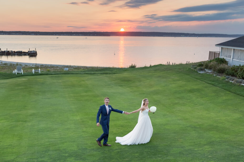 A bride drags her groom across the lawn at their wedding venue in rhode island - warwick country club